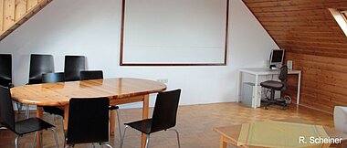 Chairs, table and a projection screen in the seminar room of the bee station