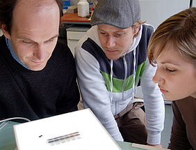 Biochemie-Professor Utz Fischer betrachtet mit den Biologie-Diplomanden Georg Stoll und Lisa Buckel das Ergebnis einer Protein-Trennung. Solche Analysen sind ein wichtiger Teil der biochemischen Forschung. Foto: Robert Emmerich