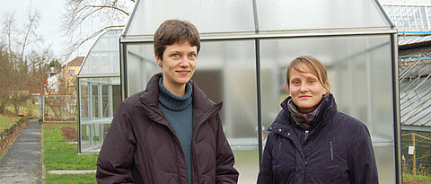 Caroline Müller (links) und Franziska Kuhlmann vom Biozentrum der Uni Würzburg vor den neuen Spezial-Gewächshäusern. Darin wollen die Forscherinnen prüfen, ob UV-Licht die Widerstandsfähigkeit von Nutzpflanzen gegen Schädlinge steigert. Foto: Rober